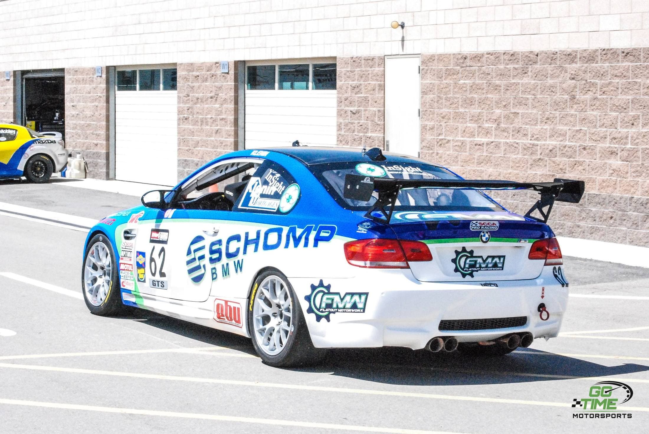 A race-prepared BMW coupe in a paddock garage