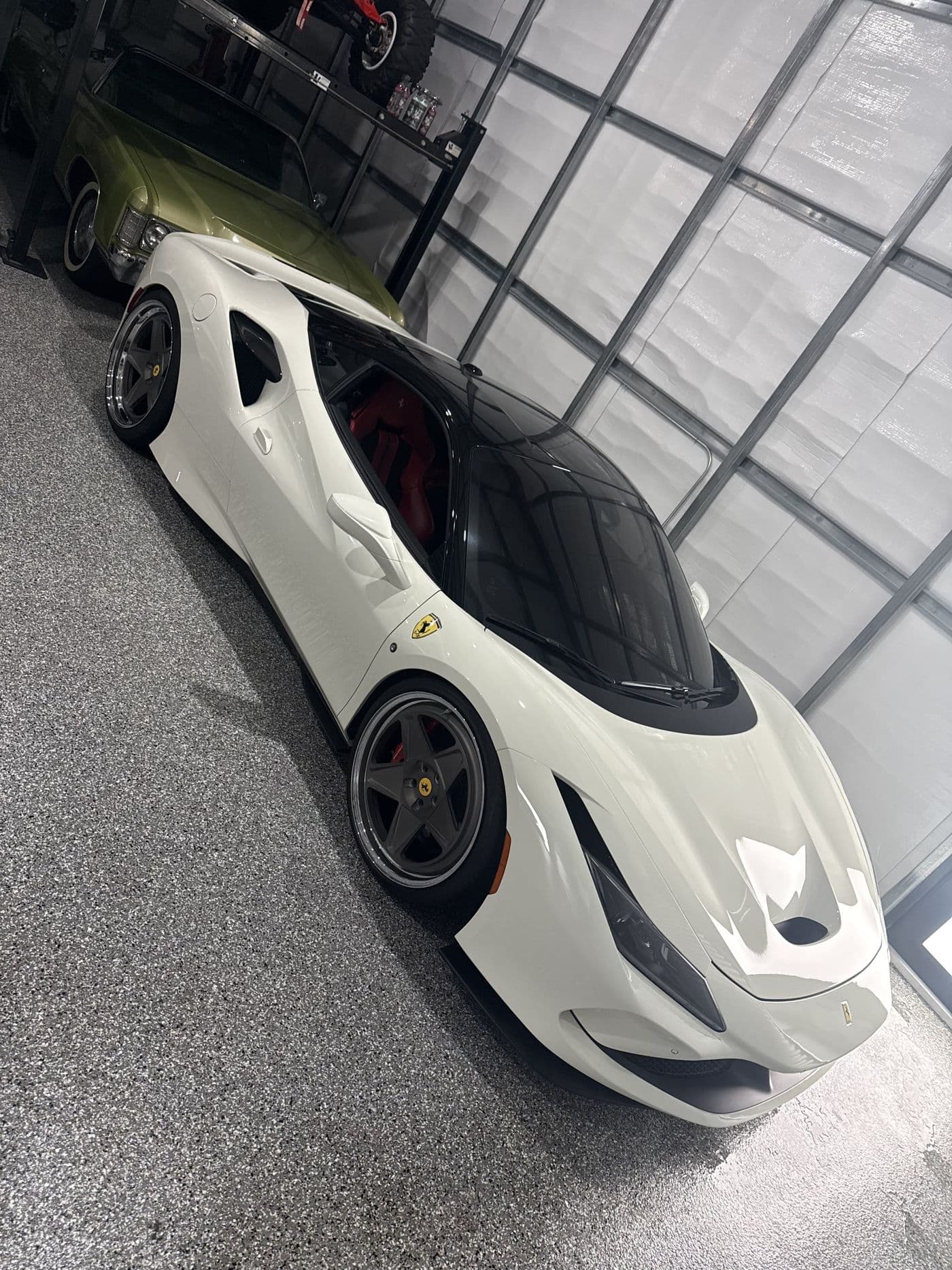 A white Ferrari F8 Tributo from the front corner, in a garage